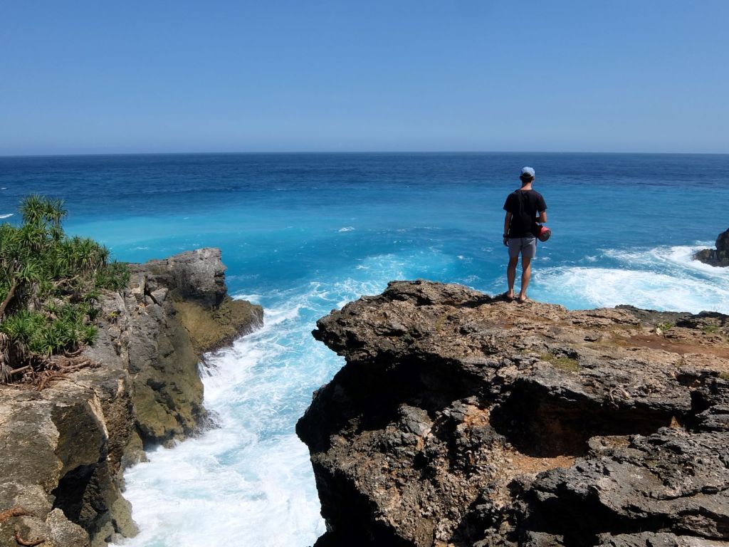 guy standing on cliff looking at ocean
