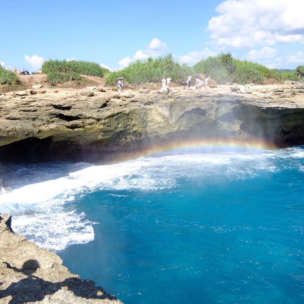 Rainbow created by the spray of water over the cliff